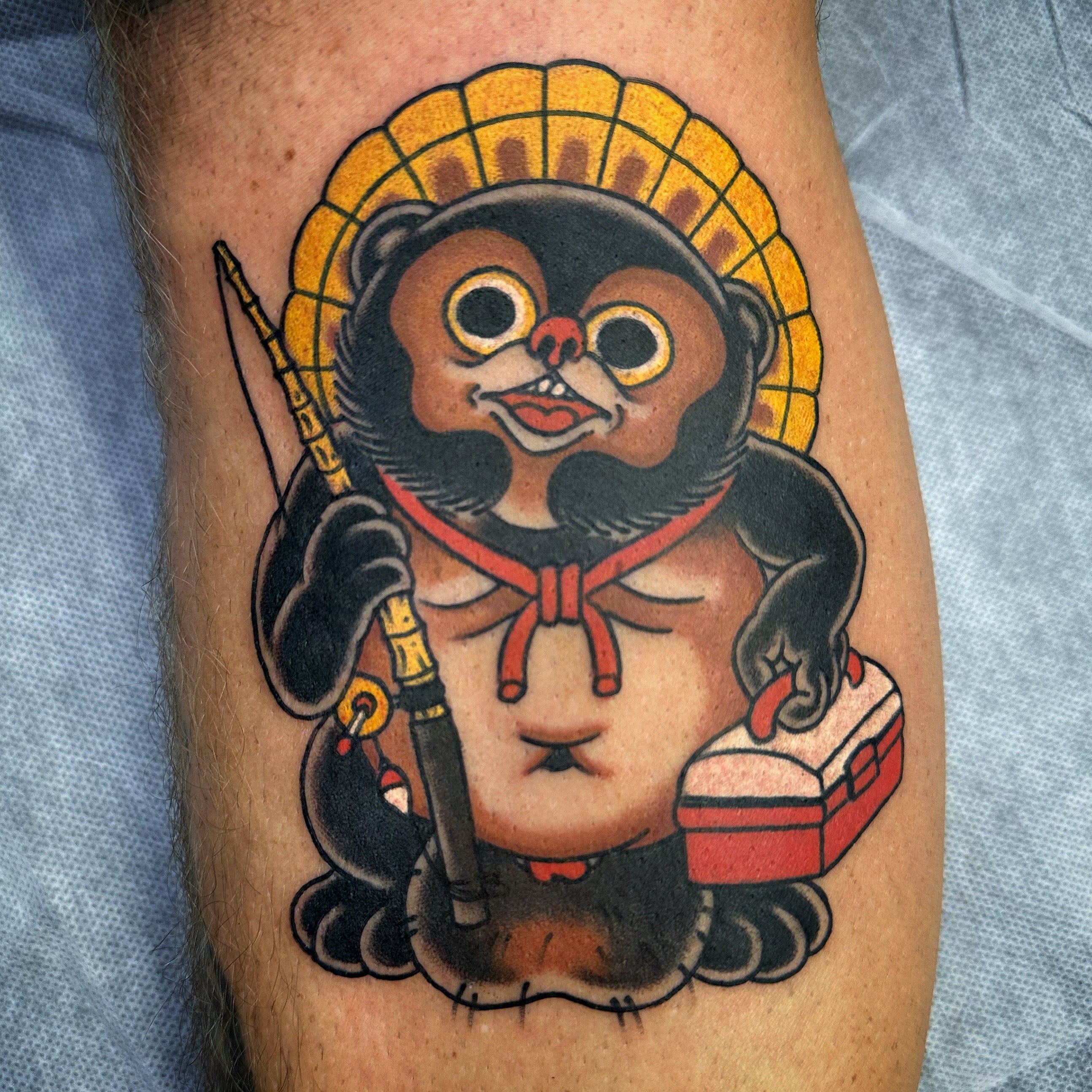 Japanese tanuki with fishing rod and tackle box tattoo